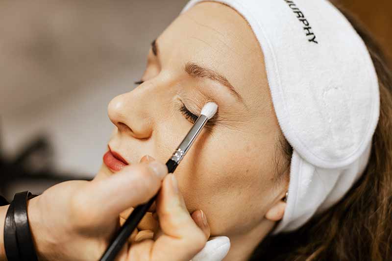 Eine Frau bekommt ein Lidstrich Make-up. Sie entspannt mit geschlossenen Augen.
